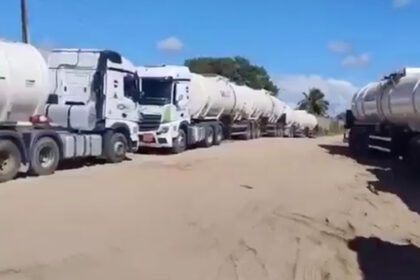 Carretas-tanque carregadas de combustível abandonadas em estrada de terra na Bahia após operação policial contra o PCC.