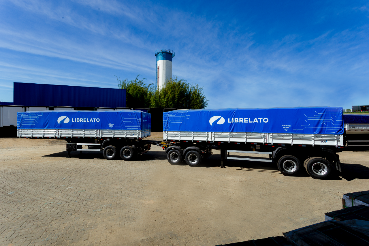 Carreta graneleira da Librelato com lona azul, estacionada no pátio industrial, simbolizando a expansão da produção em Guarulhos.