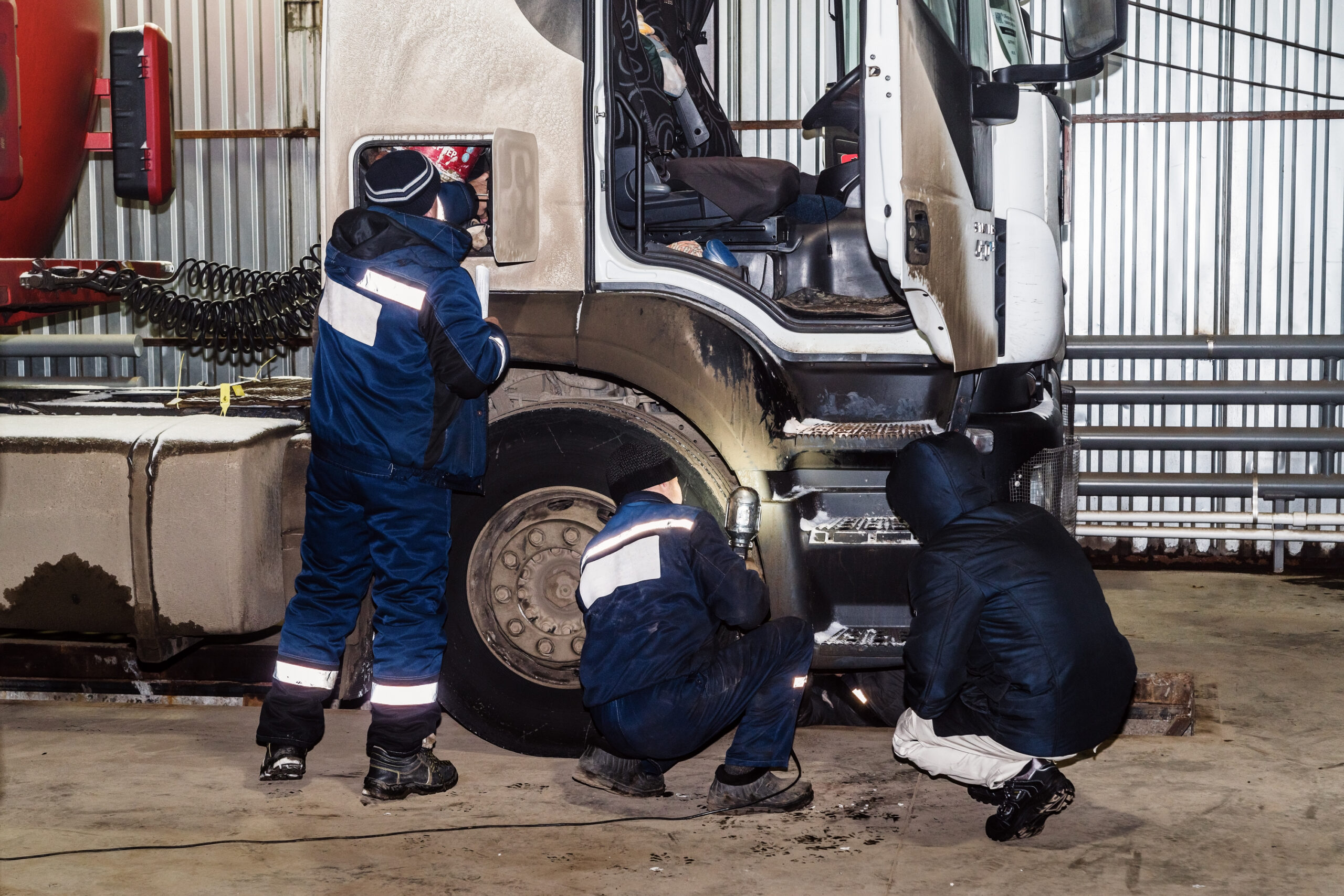 Técnicos inspecionando freios de caminhão em oficina durante o inverno