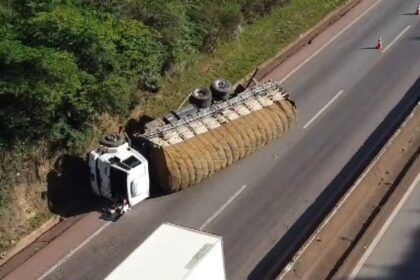 Caminhão de carga tombado na rodovia, interditando uma das faixas de tráfego.