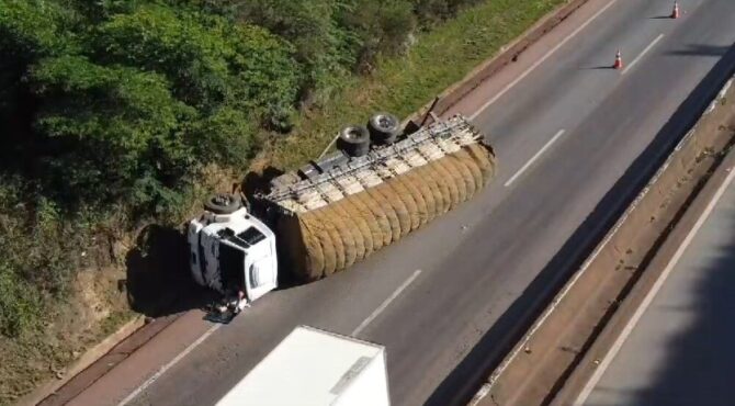 Caminhão de carga tombado na rodovia, interditando uma das faixas de tráfego.
