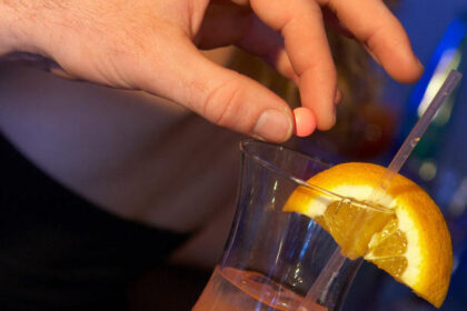 Close-up de uma mão segurando um objeto transparente próximo a um drink .