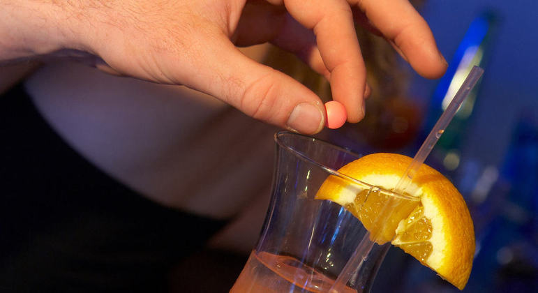 Close-up de uma mão segurando um objeto transparente próximo a um drink .