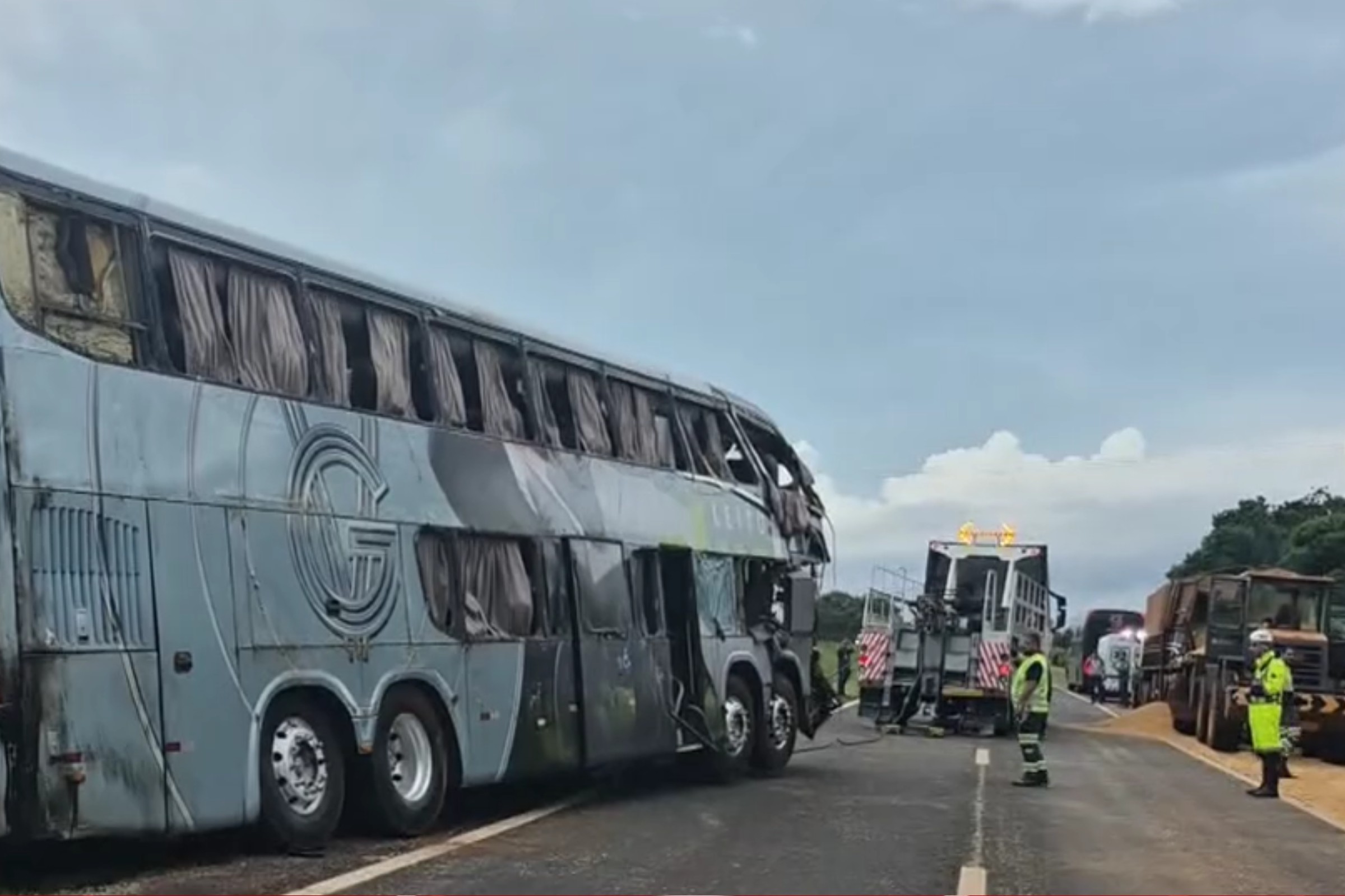 Ônibus parado no acostamento de uma rodovia, com trânsito ao lado e veículos à frente.