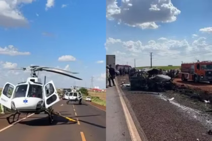 Helicóptero pousado às margens de uma rodovia, com veículos parados e congestionamento de caminhões na pista.