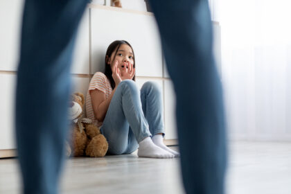 Menina assustada sentada no chão, olhando para um homem