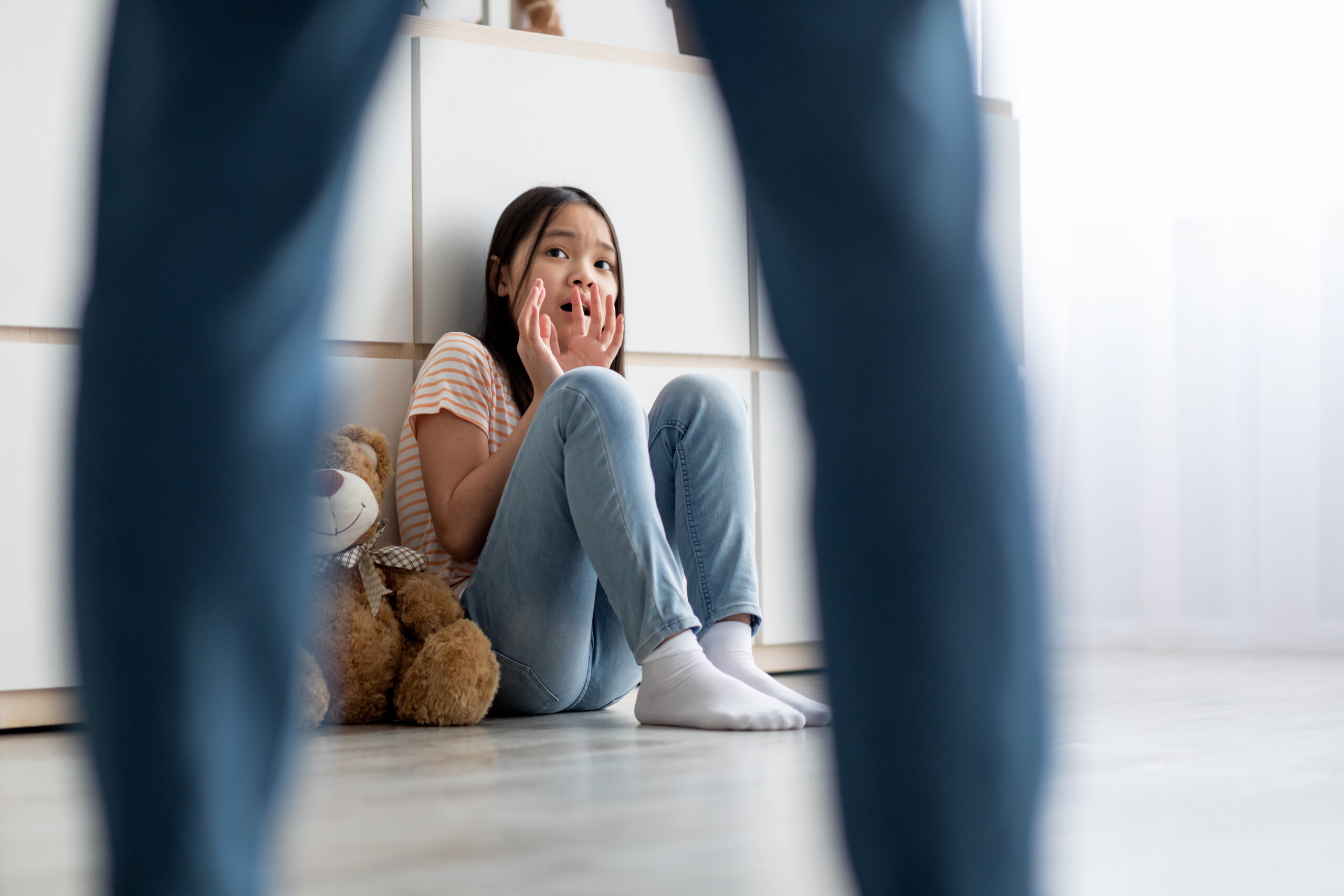 Menina assustada sentada no chão, olhando para um homem